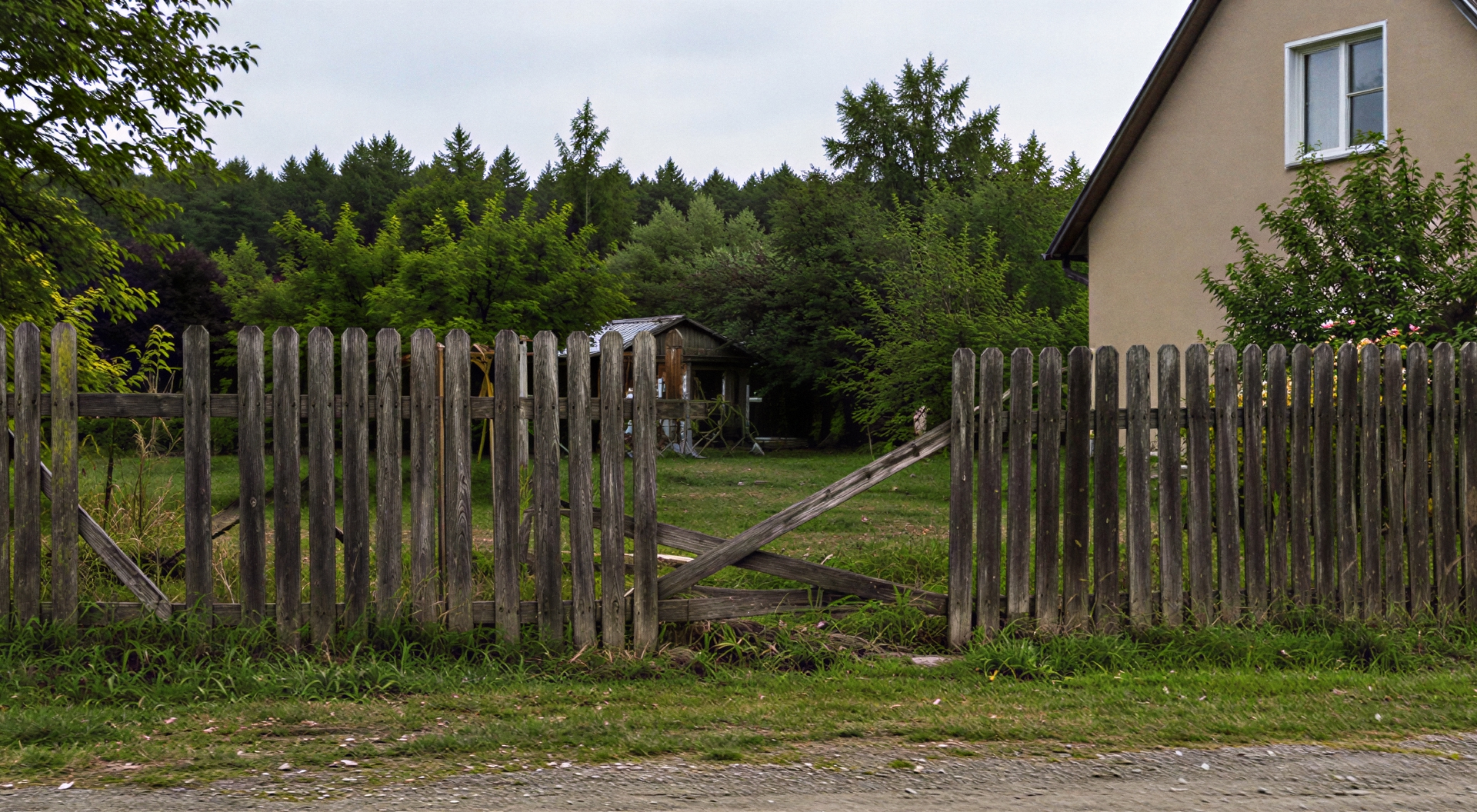 Działka przed wymianą ogrodzenia ze starym, krzywo stojącym płotem drewnianym